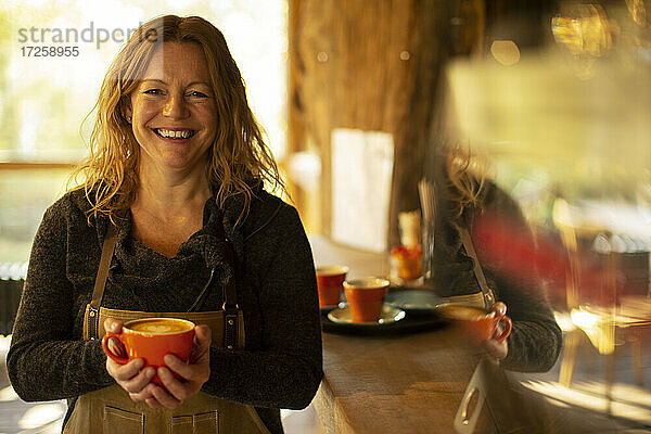 Porträt glückliche weibliche Kaffeehausbesitzerin mit Cappuccino