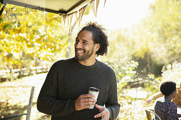 Glücklicher Mann mit Kaffee im sonnigen Herbst Park