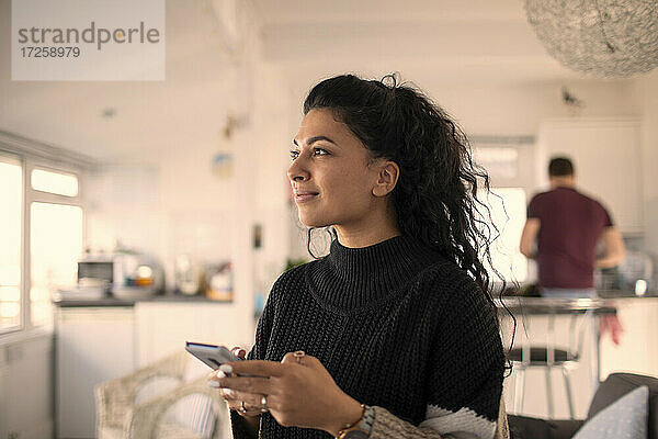 Lächelnde schöne Frau mit Smartphone zu Hause