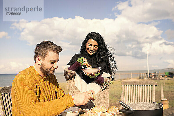 Paar genießt Chowder und Baguette auf der sonnigen Strandterrasse