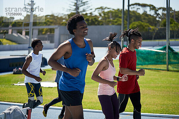 Lächelnd Leichtathleten laufen auf sonnigen Sportbahn