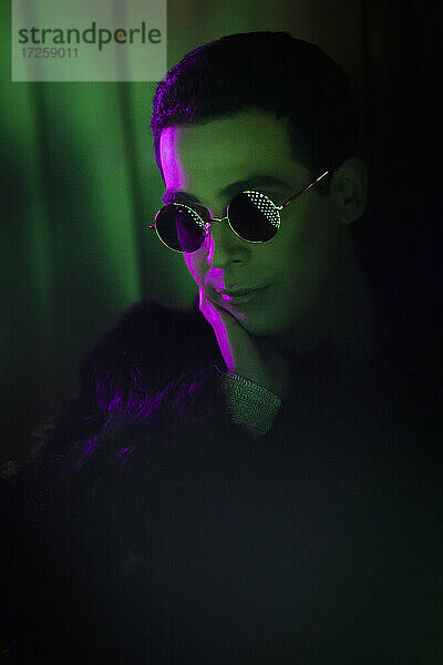Stilvoller junger Mann mit Sonnenbrille im Dunkeln