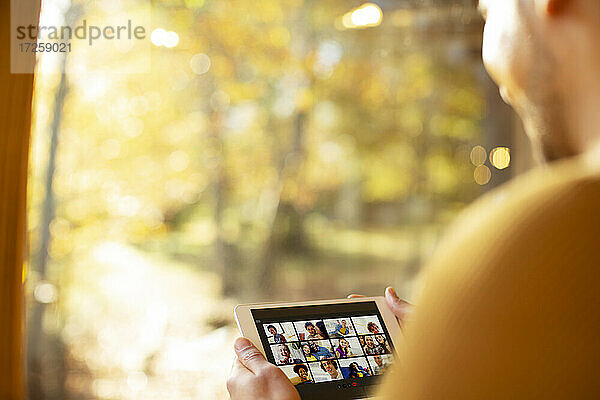 Mann Video-Chat mit Freunden auf digitalen Tablette an sonnigen Fenster