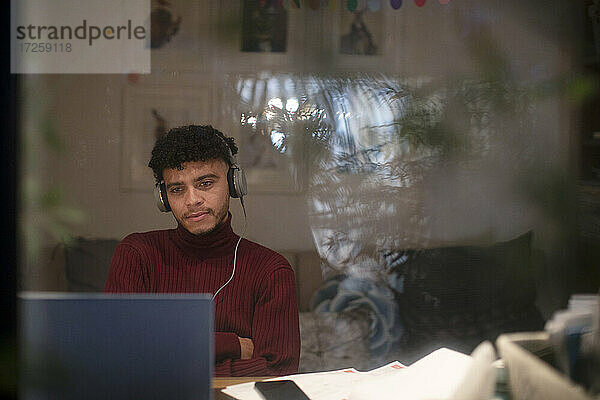 Konzentrierter junger Mann arbeitet nachts am Laptop im Heimbüro