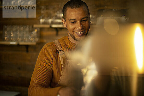 Lächelnde männliche Barista bereitet Kaffee im Café