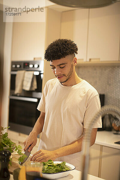 Junger Mann Kochen Schneiden von Gemüse auf Küchentheke