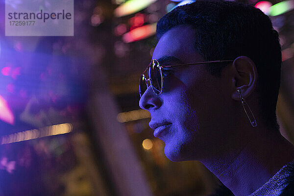 Close up stilvollen jungen Mann mit Sonnenbrille unter Neonlicht