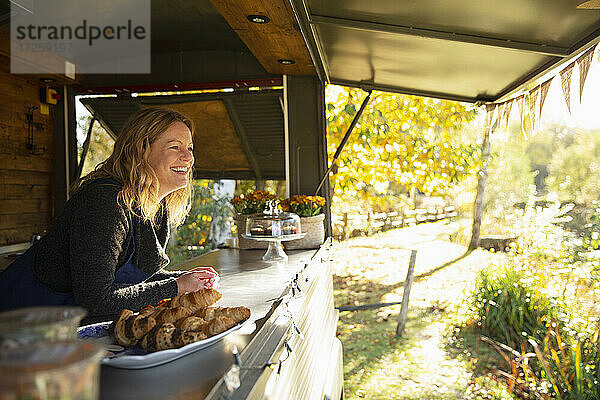 Glückliche weibliche Essen Wagen Besitzer in sonnigen Herbst Park