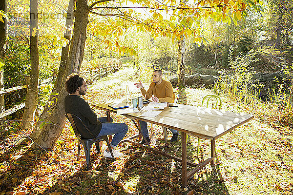 Geschäftsleute treffen sich am Tisch im sonnigen idyllischen Herbstpark