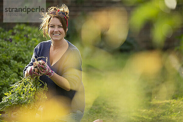 Porträt glücklich zuversichtlich  Frau erntet frische Kartoffeln im Garten