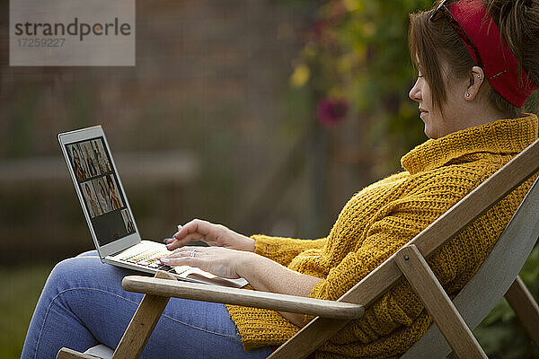 Frau mit Laptop im Liegestuhl