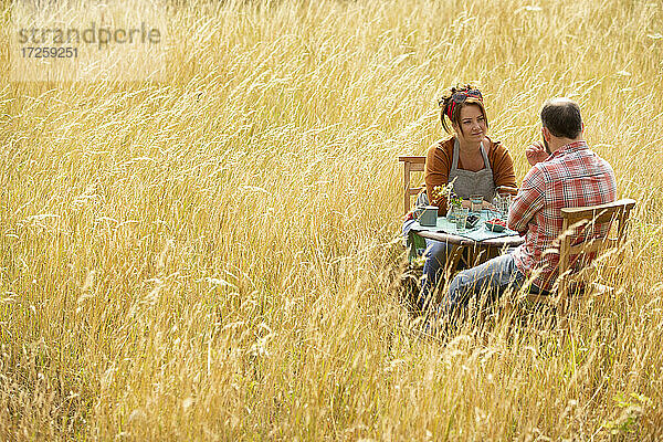 Paar genießt Obst am Tisch in sonnigen Sommer Feld von hohem Gras