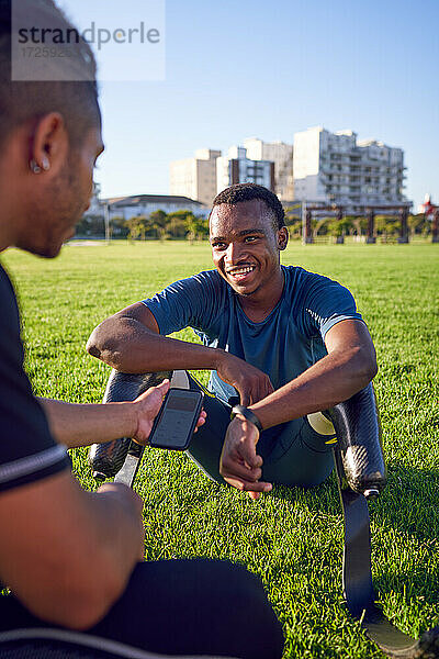 Trainer im Gespräch mit einem jungen männlichen amputierten Sportler im Park