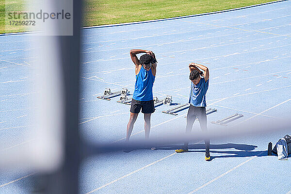 Männliche Läufer Stretching auf sonnigen blauen Sportbahn
