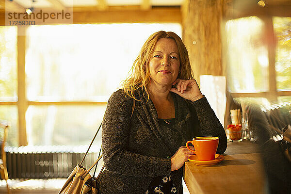 Porträt glückliche Frau bestellt Cappuccino im Café Theke