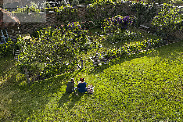 Ehepaar macht eine Pause von der Gartenarbeit in sonnigen idyllischen üppigen Garten