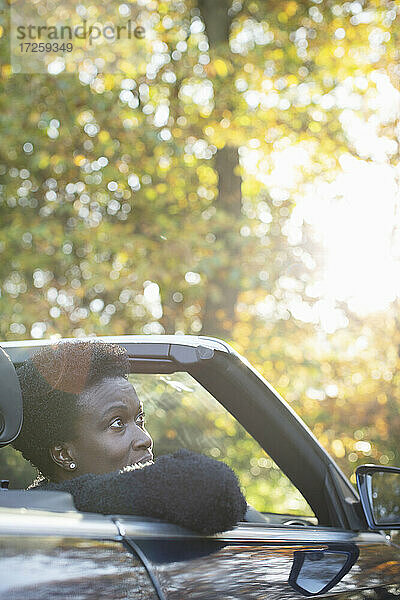 Frau fährt im Cabrio in sonnigen Herbst Park