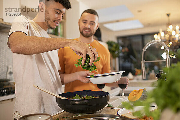 Homosexuell männliches Paar Kochen mit frischem Spinat in der Küche