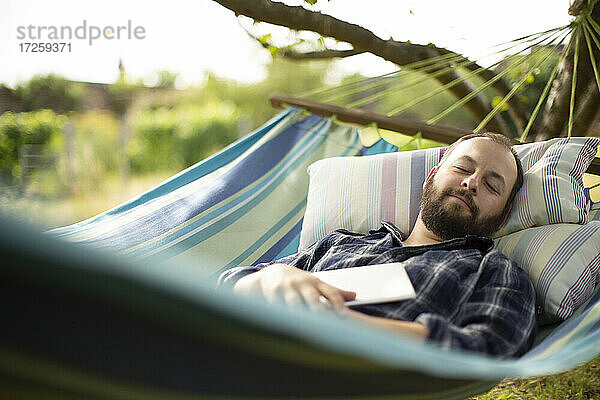 Serene Mann mit digitalen Tablette schlafen im Hinterhof Sommer Hängematte