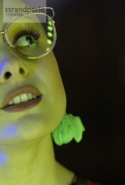 Close up schöne stilvolle Frau in Retro-Brille in grünem Licht