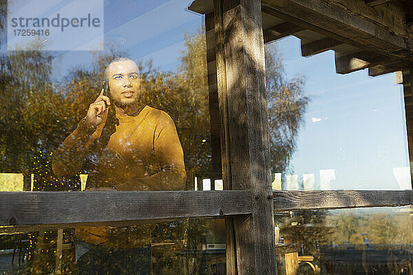 Mann spricht auf Smartphone an sonnigen Restaurant Fenster