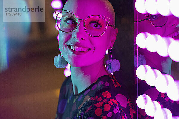Close up Porträt schöne Frau mit rasiertem Kopf  Kopf durch Neonlicht