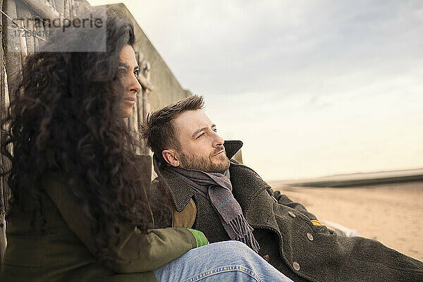 Serene Paar im Winter Mantel entspannt am Strand