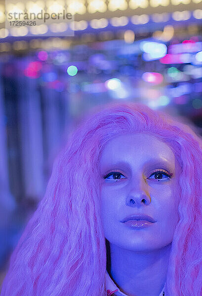 Porträt selbstbewusste kühle Frau mit rosa Haaren unter Neonlicht