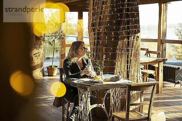 Weibliche Kleinunternehmerin trinkt Kaffee am sonnigen Cafe-Tisch