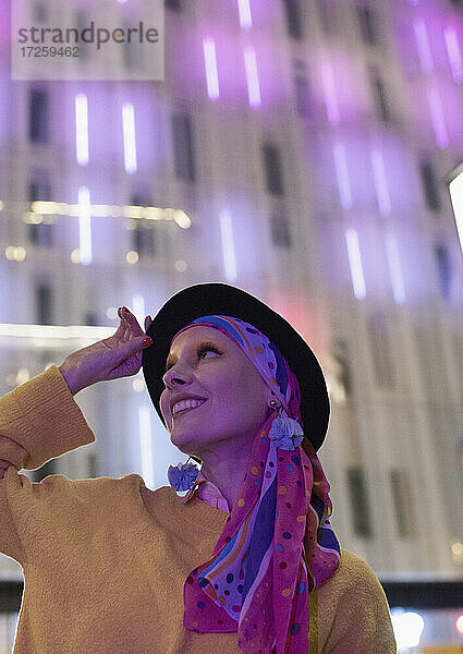 Porträt modische glückliche Frau Blick auf Neon Gebäude