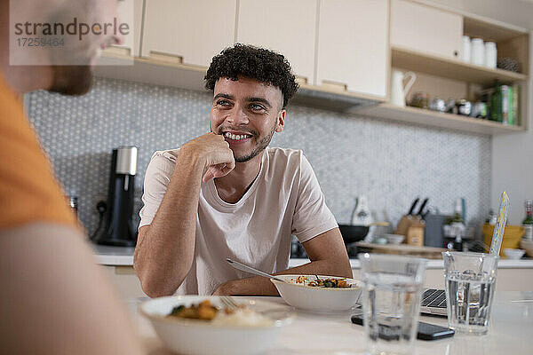 Lächelnde Homosexuell männliches Paar im Gespräch und Essen in der Küche