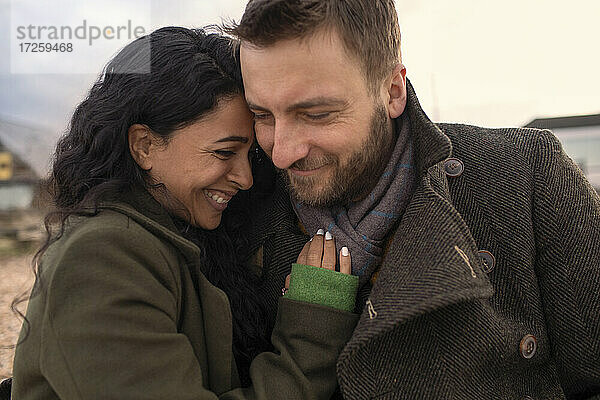 Glückliches  liebevolles Paar in Wintermänteln  das sich umarmt