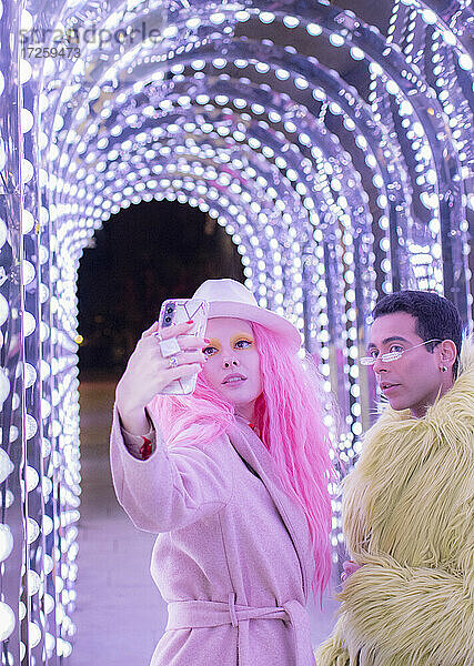 Stilvolles Paar nimmt Selfie unter Bogen Lichter