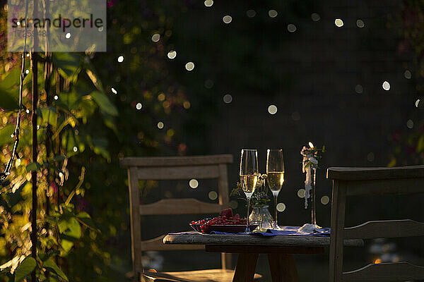 Champagnerflöten und rote Johannisbeeren auf dem Tisch im idyllischen Sommergarten