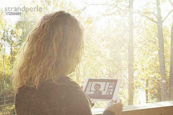 Frau Video-Chat mit Freunden auf digitalen Tablette an sonnigen Fenster