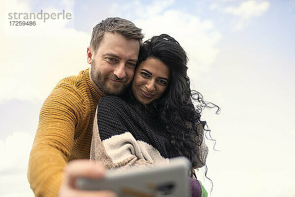 Glücklich zärtliches Paar in Pullover nehmen selfie