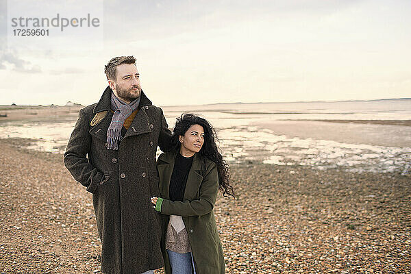 Zärtliches Paar in Wintermäntel zu Fuß auf Ozean Strand