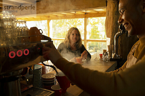 Barista bereitet Kaffee für Kunden an Espressomaschine im Café