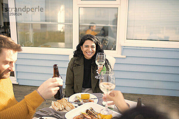 Glückliche Frau genießt Wein und Meeresfrüchte mit Freunden auf der Terrasse Tisch