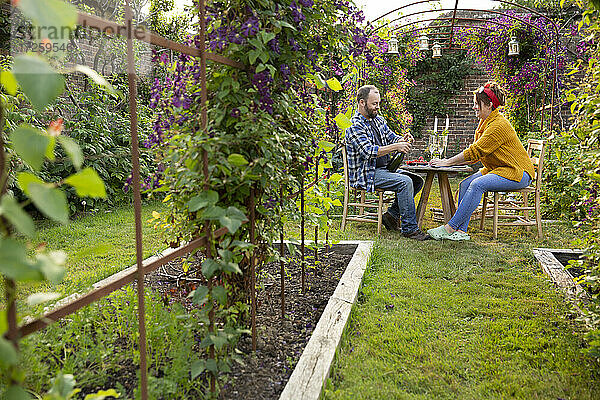 Paar genießt Champagner und rote Johannisbeeren am Tisch im Sommergarten