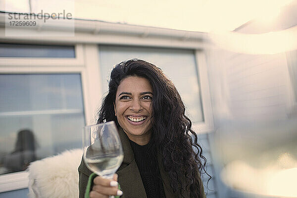 Glückliche sorglose Frau genießt Weißwein auf der Terrasse