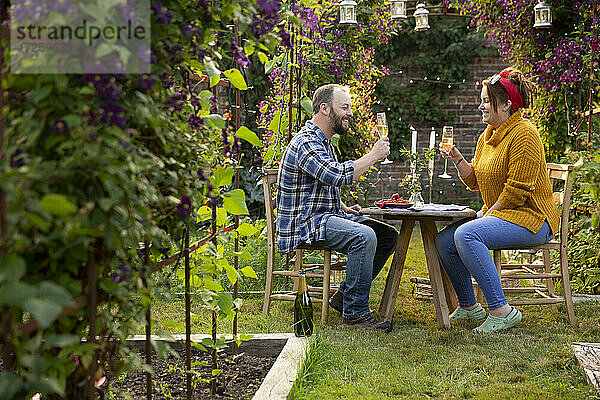 Paar genießt Champagner am Tisch im idyllischen Sommergarten