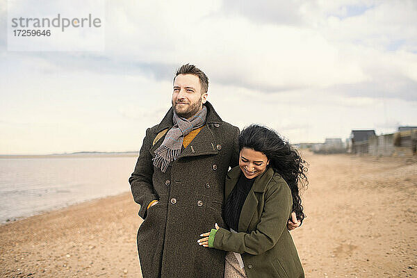 Glückliches Paar in Wintermäntel zu Fuß auf Ozean Strand