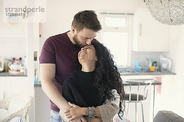 Glücklich zärtliches Paar umarmt und küsst in der Küche