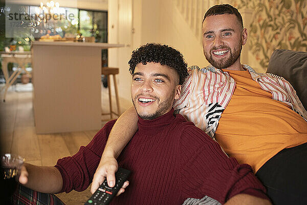 Glückliche Homosexuell männliches Paar vor dem Fernseher auf dem Sofa