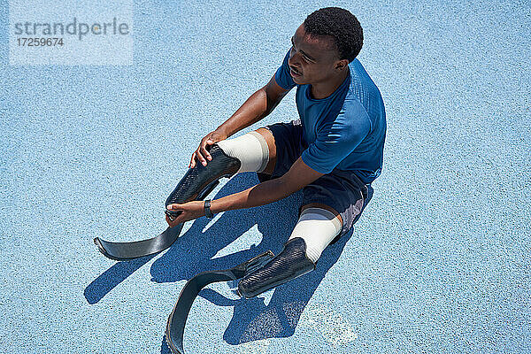 Männlicher amputierter Sprinter bei der Vorbereitung auf der blauen Sportbahn