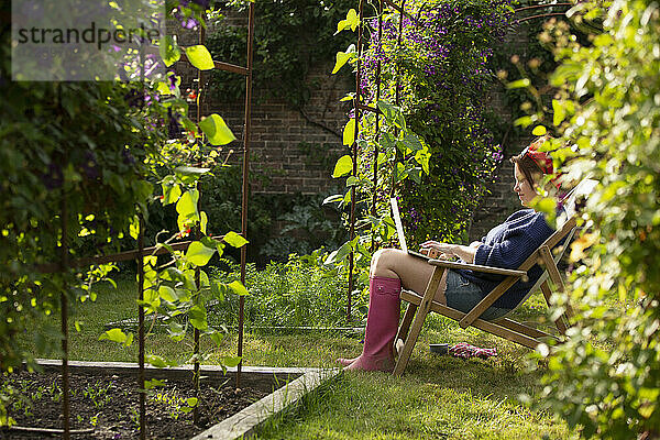 Frau mit Laptop in sonnigen Sommergarten