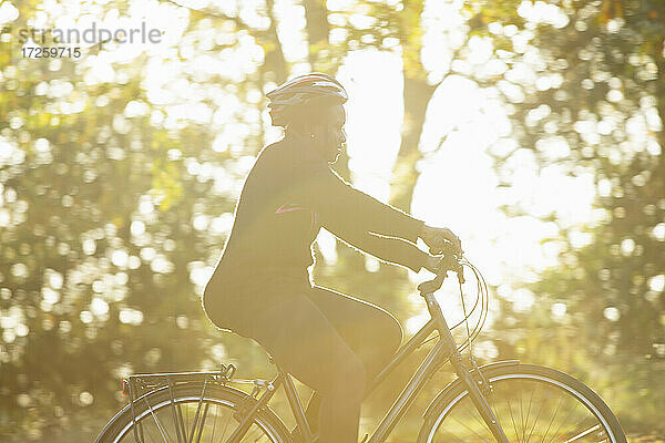 Frau in Helm Fahrradfahren in sonnigen Herbst Park