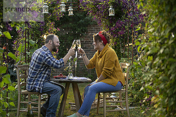 Glückliches Paar stößt mit Champagner im idyllischen Sommergarten an