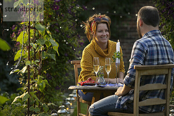 Glückliches Paar genießt Champagner am Gartentisch